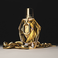 Facettierter goldener Parfumflakon Million Gold for Her von Rabanne mit goldener Kette auf dunklem Hintergrund.