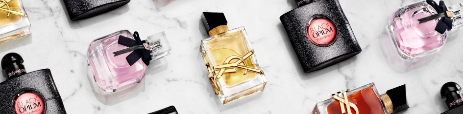 Kategoriebanner Damendüfte von Yves Saint Laurent: Mehrere Parfumflakons, darunter Black Opium und weitere YSL-Düfte, liegen dekorativ verteilt auf einer hellen Marmoroberfläche, teils mit schwarzer oder goldfarbener Verpackung.